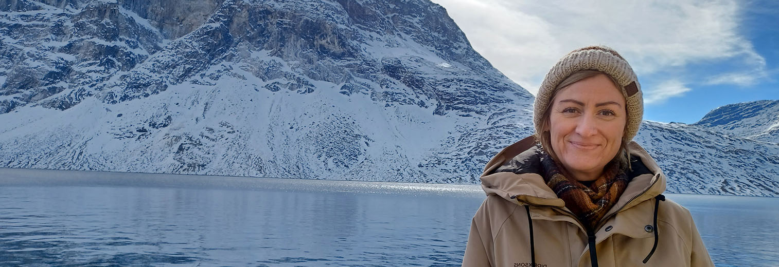 Teilnehmerin in Winterkleidung vor Schneelandschaft am Meer in Grönland