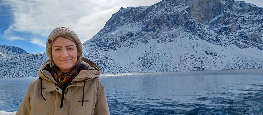 Eine Frau steht vor einer Winterlandschaft mit Meer und Bergen